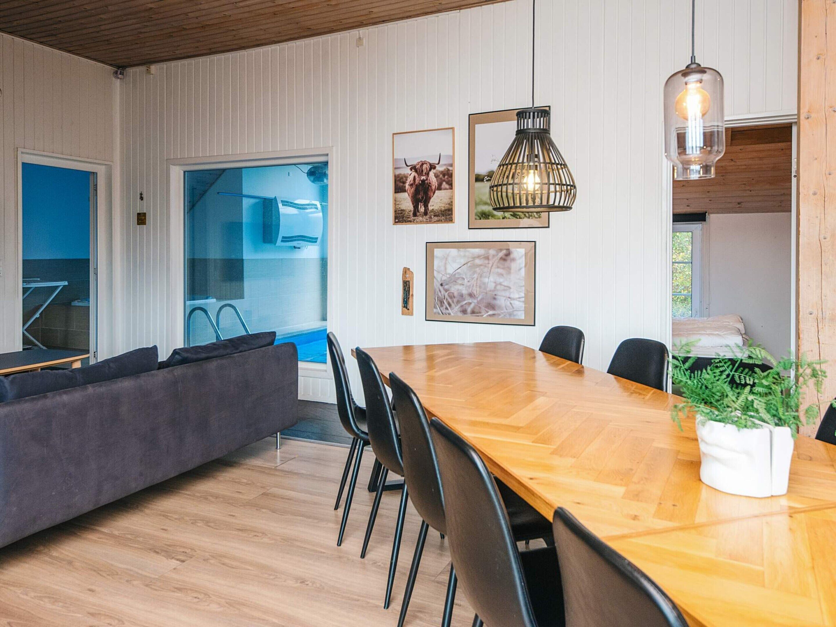 Ein modernes Wohnzimmer mit einem Holzesstisch, schwarzen Stühlen, einem grauen Sofa und einem großen Fenster.