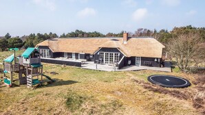 A thatched-roof building with a play area and a trampoline.