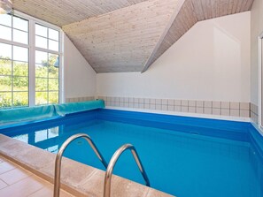 An indoor swimming pool with a wooden ceiling, tiled walls, and a clear view outside. - 4 Star Holiday Home in Fano (Fano)