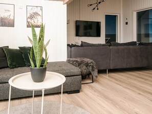 A modern living room with a grey sectional sofa, a white round table, and a potted plant. - 4 Star Holiday Home in Fano (Fano)