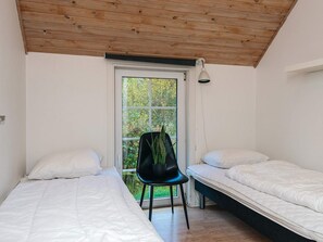 A bedroom with two beds, a chair, and a window with a view of greenery. - 4 Star Holiday Home in Fano (Fano)