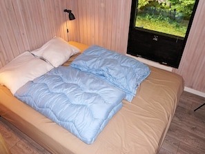 A bed with a beige mattress and blue bedding, a black lamp, and a window with a view of greenery. - 6 Person Holiday Home in Tjornarp (Tjörnarp)
