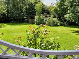 A well-maintained garden with a wooden fence, a small shed, and various plants.