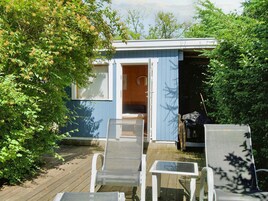 A small blue building with a door open, a white chair, and a table outside.