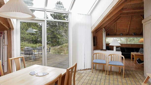 A cozy dining area with wooden furniture and a large window overlooking a garden. - 8 Person Holiday Home in Fjerritslev-by Traum (Fjerritslev)