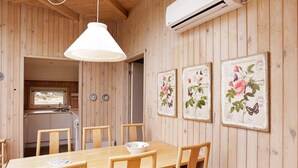 A wooden interior with a dining table, chairs, an air conditioning unit, and wall-mounted botanical prints. - 8 Person Holiday Home in Fjerritslev-by Traum (Fjerritslev)