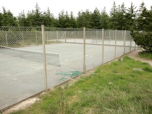 A fenced tennis court with a net, surrounded by trees and grass. - 8 Person Holiday Home in Fjerritslev-by Traum (Fjerritslev)