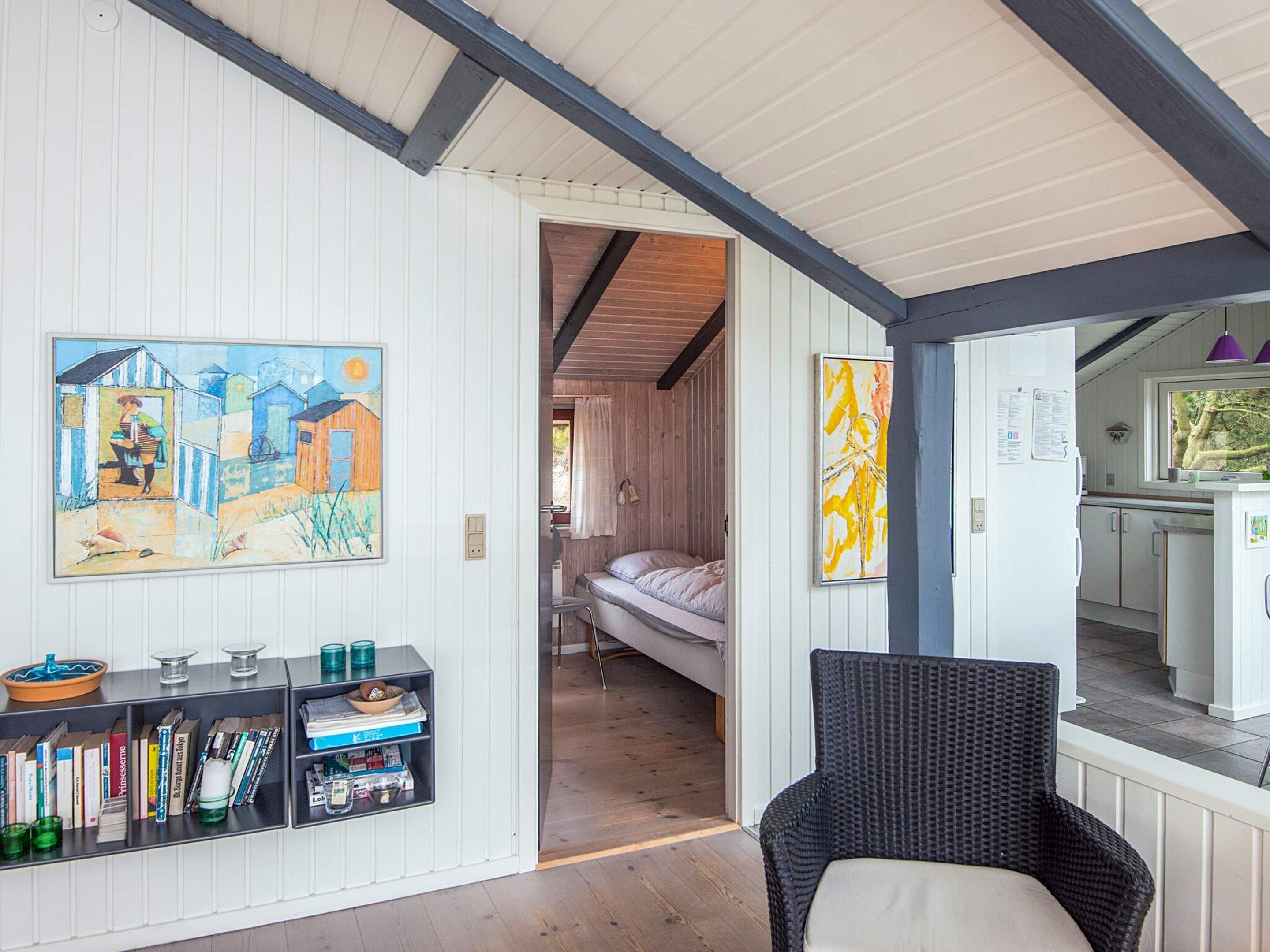 A room with a bed, a bookshelf, and a painting on the wall.