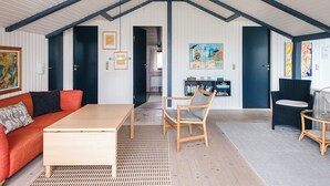 A spacious loft with high ceilings, a wooden coffee table, a red sofa, and a seating area with chairs. - 4 Star Holiday Home in Vejers Strand (Vejers Strand)