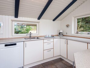 A modern kitchen with white cabinetry, a stainless steel sink, and a coffee maker. - 4 Star Holiday Home in Vejers Strand (Vejers Strand)