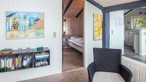A room with a bed, a bookshelf, a wicker chair, and a painting on the wall. - 4 Star Holiday Home in Vejers Strand (Vejers Strand)