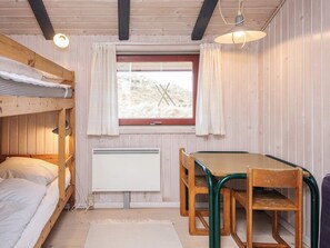 A compact room with a bunk bed, a table with chairs, a window with curtains, and a radiator. - 4 Star Holiday Home in Vejers Strand (Vejers Strand)