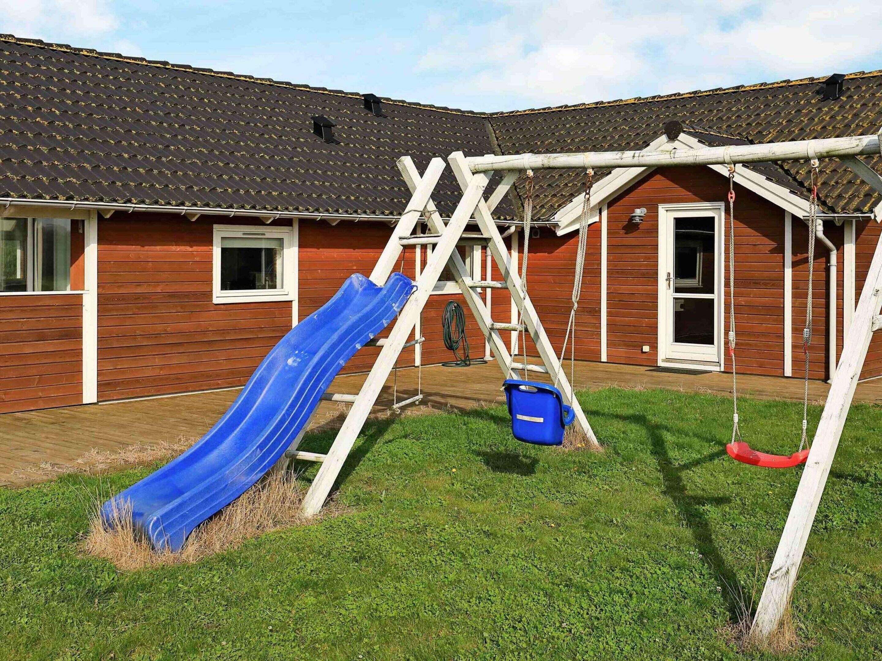 Ein Holzhaus mit einer blauen Rutsche und einer Schaukel.