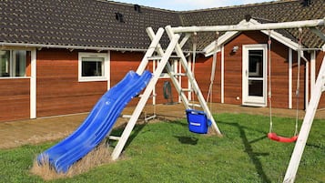 Ein Holzhaus mit einer blauen Rutsche und einer Schaukel.