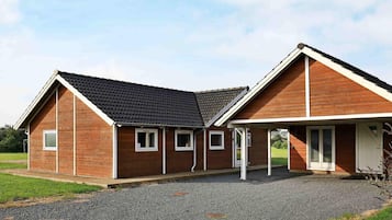 Ein zweistöckiges Holzhaus mit einem Schotterweg und einer überdachten Veranda.
