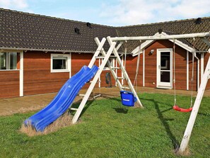 A wooden house with a red exterior, a blue slide, and a swing set.
