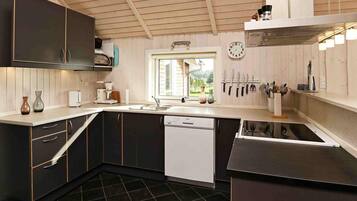 A modern kitchen with dark cabinetry, a dishwasher, and a window providing natural light.