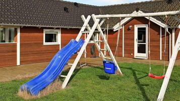 A wooden house with a blue slide and a swing set.