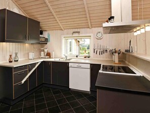 A modern kitchen with dark cabinetry, a dishwasher, and a window providing natural light. - 10 Person Holiday Home in Vaeggerlose (Vaeggerlose)