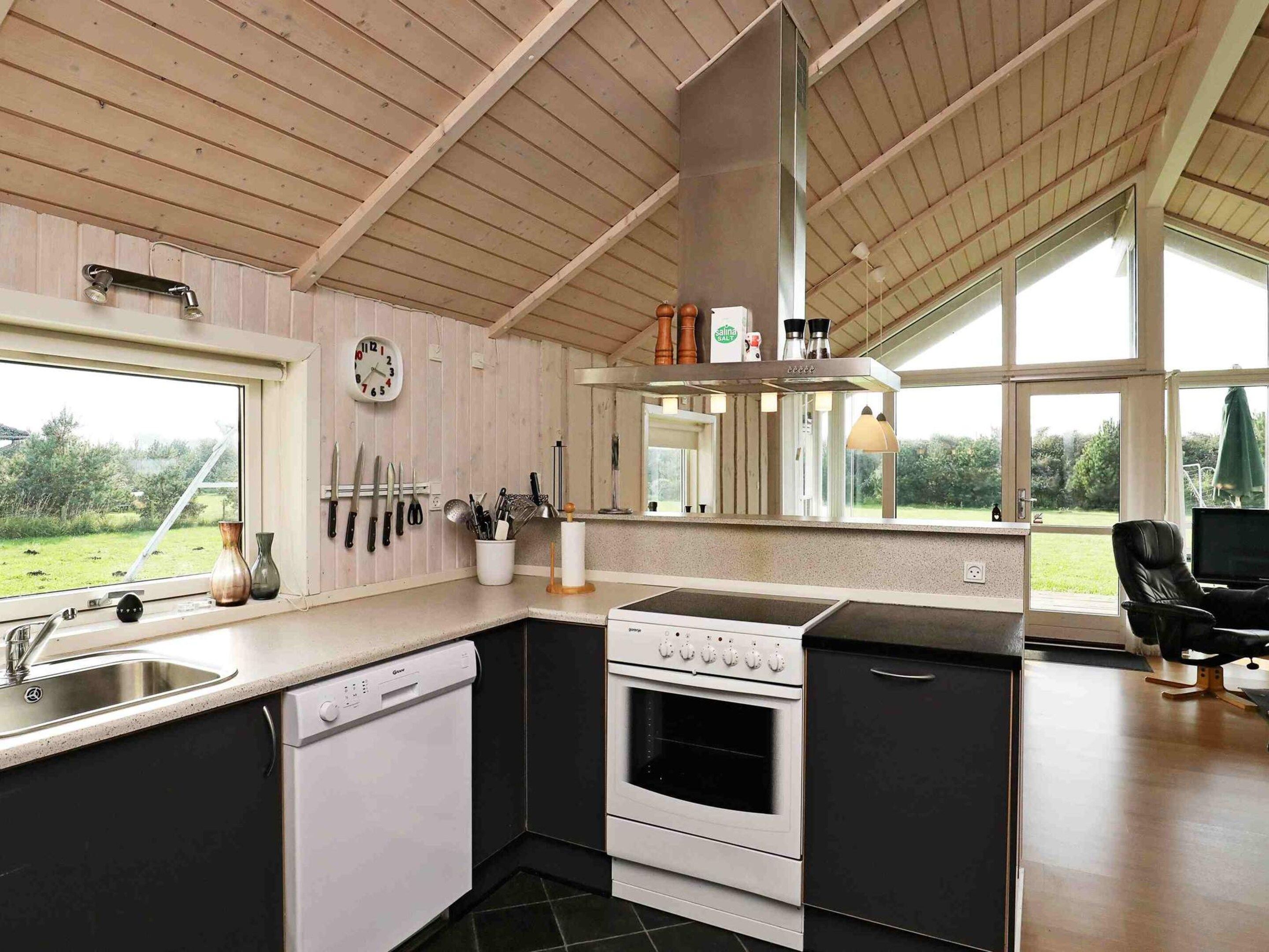 A modern kitchen with a dishwasher, stove, and a large window offering a view of the outdoors.