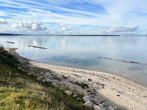 A calm lake with a sandy beach and a rocky shoreline. - 4 Star Holiday Home in Otterup (Otterup)