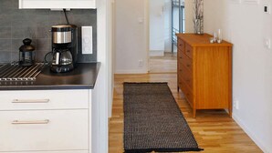 Una cocina moderna con una cafetera, un mueble de madera y una alfombra negra.