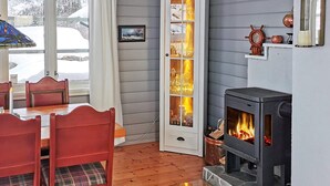 Una habitación acogedora con una mesa de comedor de madera, sillas rojas, una chimenea y un aparador con puertas de cristal.