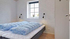 Une chambre à coucher avec un lit, une fenêtre et deux lampes fixées au mur.