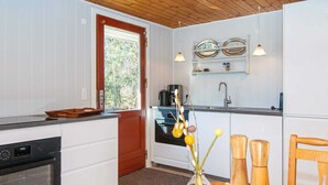 A modern kitchen with white cabinets, a wooden countertop, a coffee machine, and a sink. - 4 Person Holiday Home in Ulfborg (Ulfborg)