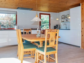 A dining area with a wooden table and chairs, a pendant light, and a view of the outdoors. - 4 Person Holiday Home in Ulfborg (Ulfborg)