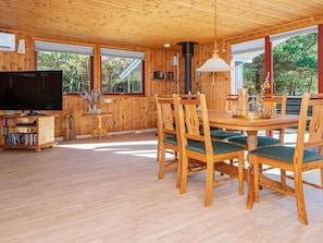 A wooden interior with a dining table, chairs, a TV, and large windows. - 4 Person Holiday Home in Ulfborg (Ulfborg)