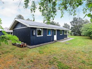 A single-story building with a dark exterior, a front porch, and a small front yard.
