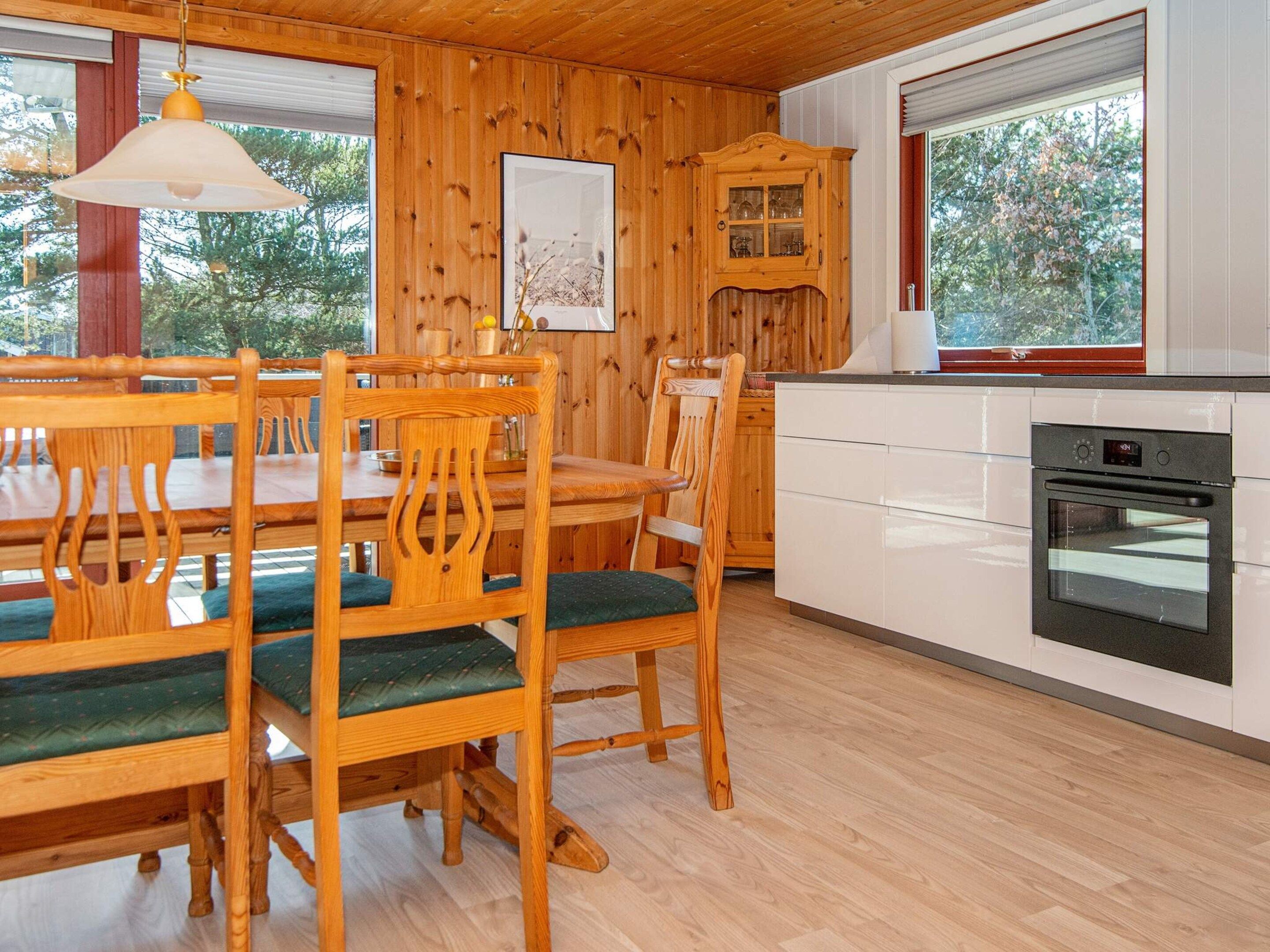 Un interior de madera con una mesa de comedor, sillas, un armario y un horno.