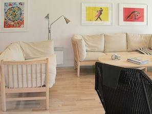 A living room with a wooden chair, a sofa, a round coffee table, and a floor lamp. - 5 Star Holiday Home in Albaek (Aalbaek)