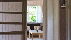 A room with a wooden floor, a sofa with cushions, a table with a candle, and a window with curtains. - 4 Star Holiday Home in Albaek (Aalbaek)