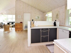 A spacious kitchen with wooden walls, a central island with a sink, and a dining area with a sofa and table.