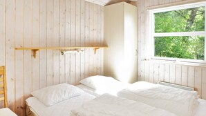 A room with two beds, wooden walls, a window with a view of trees, and a hanging light fixture. - 4 Star Holiday Home in Albaek (Aalbaek)
