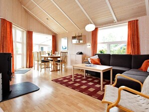 A spacious living area with a wooden ceiling, a sofa, a dining table with chairs, and a TV. - Holiday Home in Otterndorf (Otterndorf)