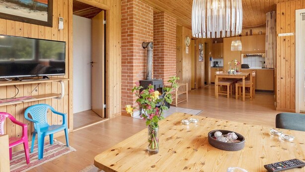 A cozy living room with a TV, a fireplace, a dining area, and a kitchen. - Secluded Holiday Home in Jutland near Beach (Hals)