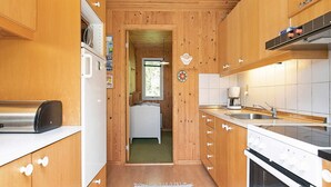 A compact kitchen with wooden cabinets, a built-in oven, a coffee maker, and a sink. - Secluded Holiday Home in Jutland near Beach (Hals)