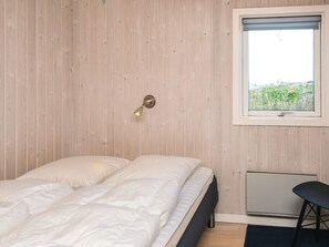 A bedroom with a bed, a wall-mounted light, a window, and a radiator.