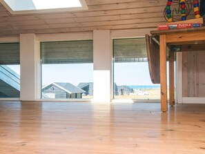 A spacious room with large windows, a wooden floor, and a puzzle on a table.