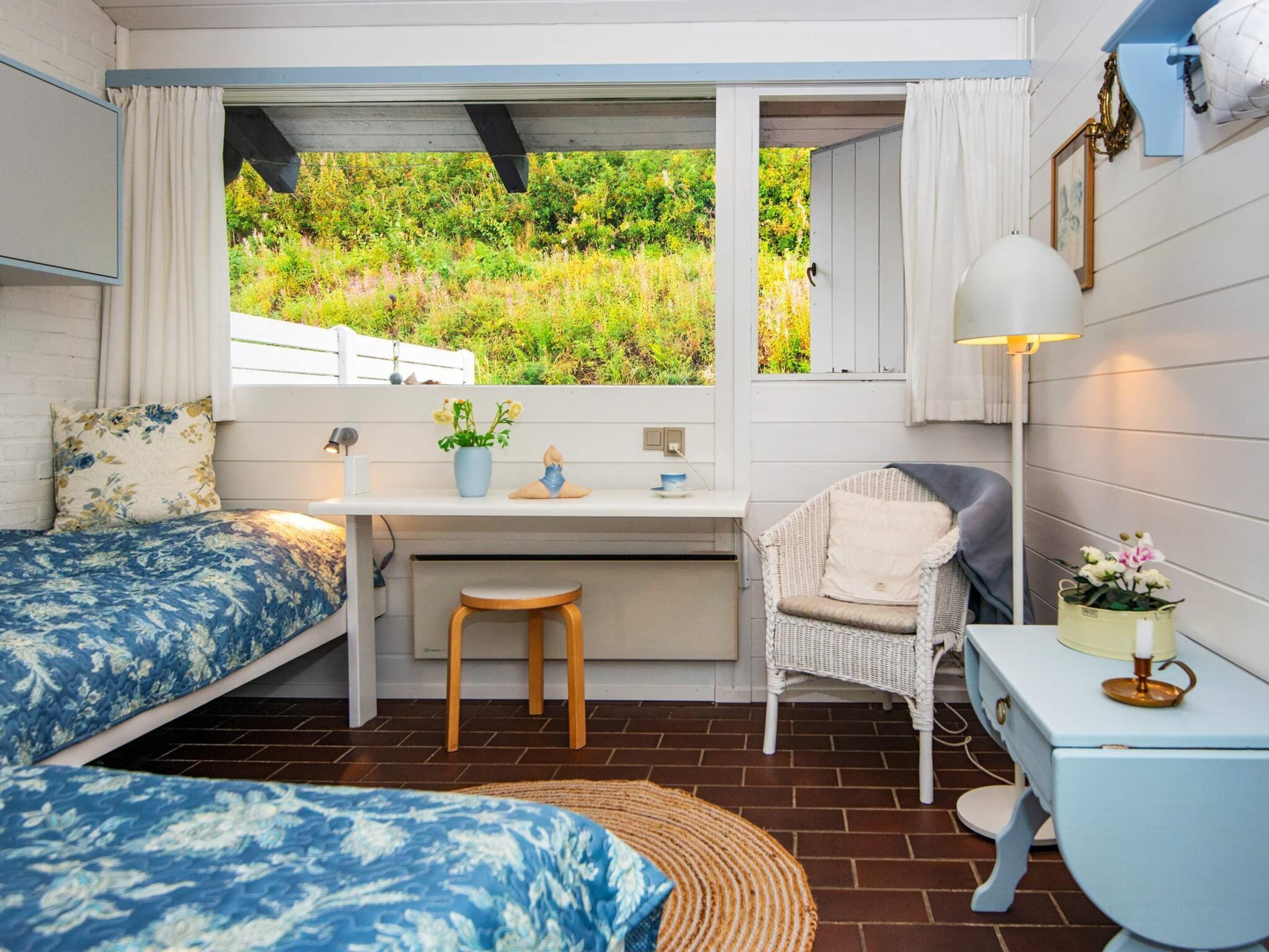 Ein gemütliches Schlafzimmer mit Bett, Schreibtisch, Stuhl und Blick ins Grüne.