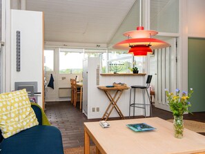 Un espace de vie compact comprenant un coin repas, une cuisine et un coin salon avec une table et des chaises.