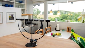 Cozinha com castiçal preto, mesa de madeira e janela com vista para o verde.