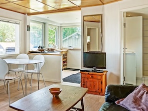 Ein stilvolles Wohnzimmer mit Essbereich, Fernseher und Küchenzeile.