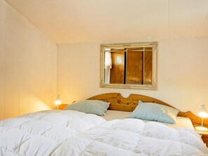 Ein Schlafzimmer mit einem hölzernen Kopfende, einem großen Spiegel und zwei Nachttischlampen.