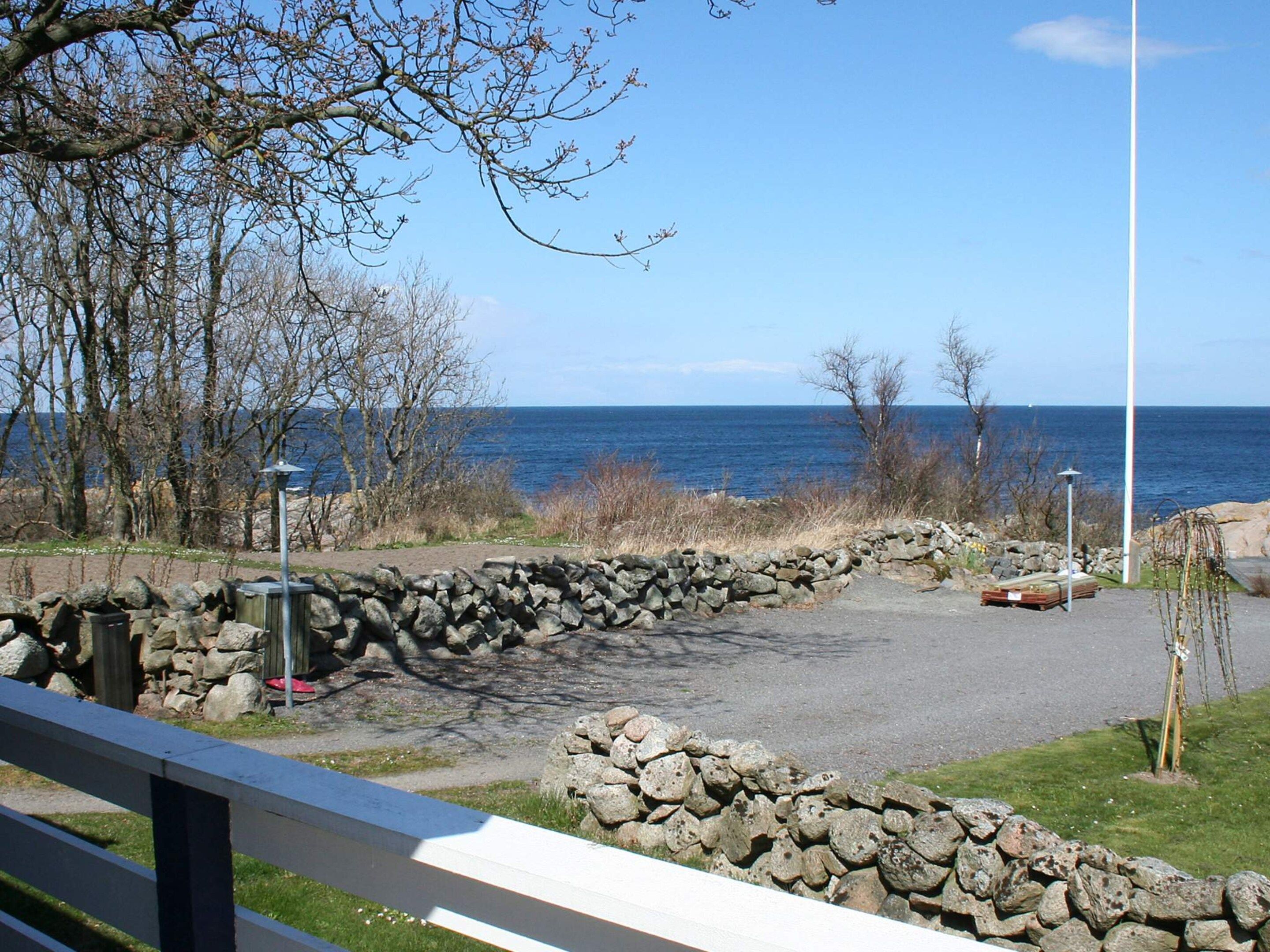 Un parque costero con un muro de piedra, bancos y vistas al mar.