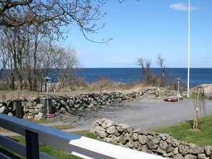 A coastal park with a stone wall, benches, and a view of the sea.