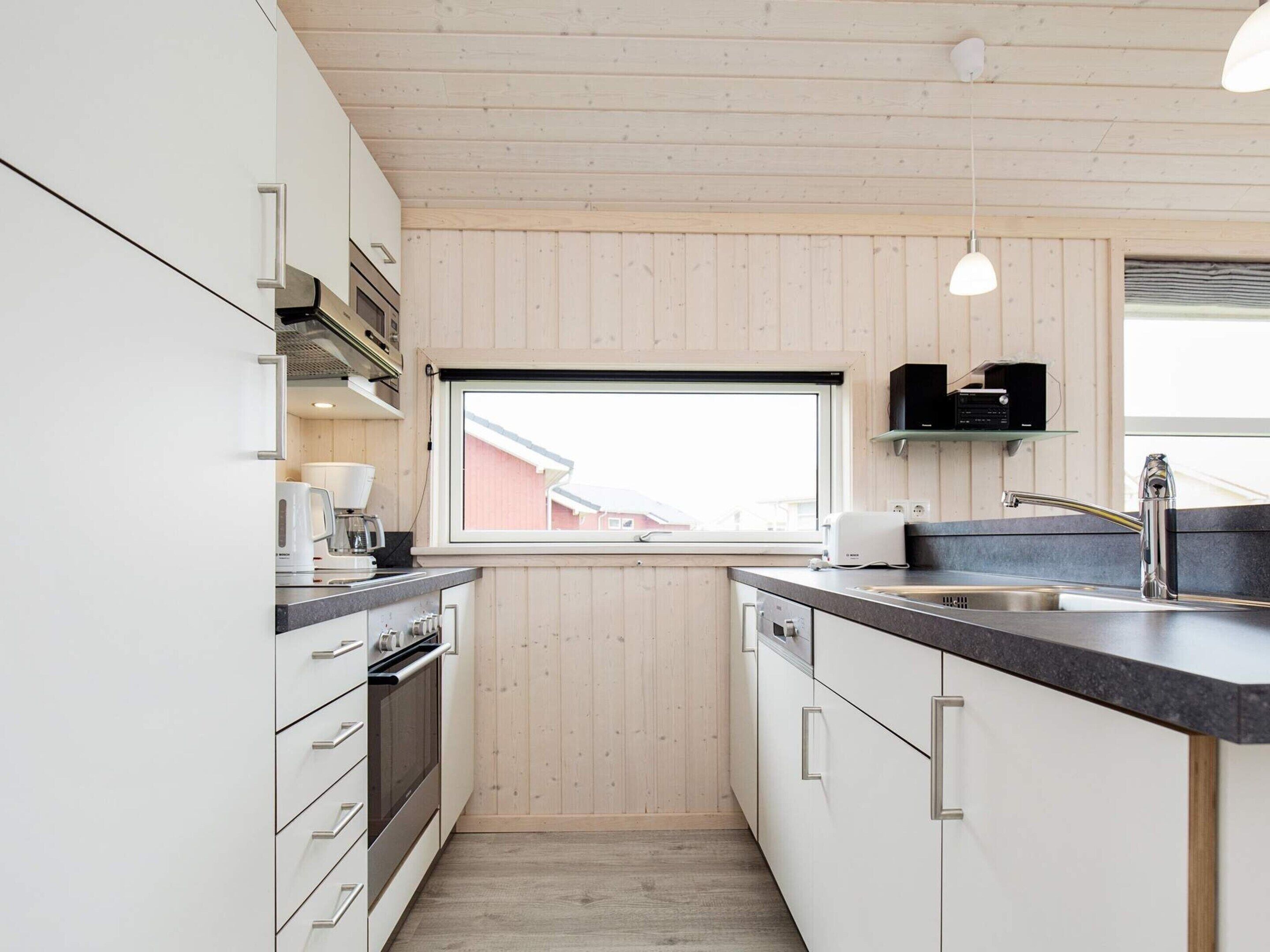 A modern kitchen with white cabinets, a black countertop, and a window providing a view of the outside.